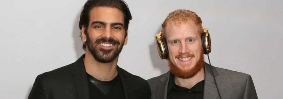 Deaf model Nyle DiMarco and Deaf Twin brother, DJ Nico DiMarco standing next to each other smiling. Nico is wearing headphones