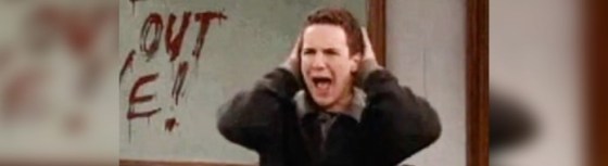 Image of a man covering his ears screaming. Wearing a brown jumper