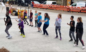 A group of people following Chris Fonseca's dance performance in front of them.