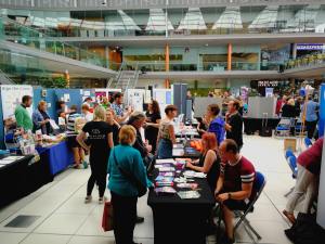 Lots of tables and Stallholders sitting down or standing and interacting with the public at the SDF 2018. Information is on their tables and display boards are all around
