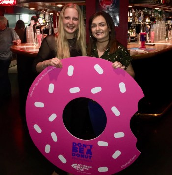 Me and Louise smiling holding a big cutout of a donut